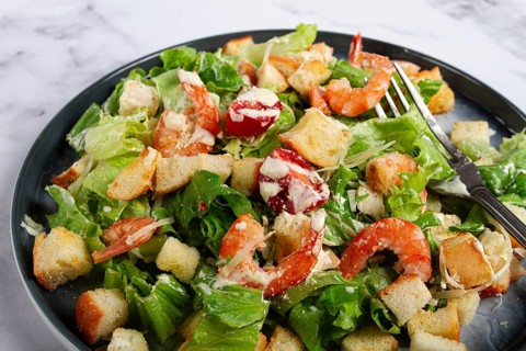 Caesar salad, with shrimp, on a marble background, top view, no people