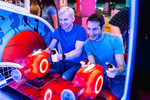 Two male friends are enjoying their time together playing an arcade racing game, showcasing the