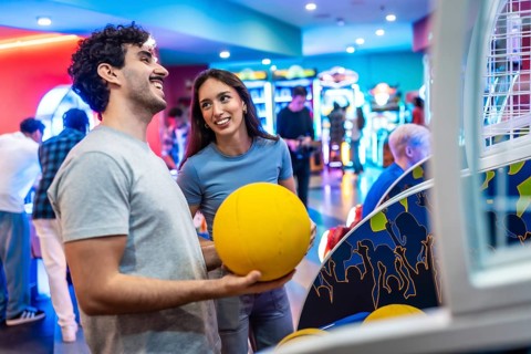 Young multiethnic couple having fun playing arcade basketball together, enjoying their weekend