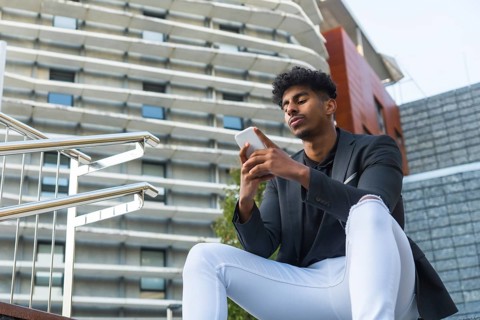 Low angle view photo with copy space of a relaxed arab young businessman using phone outdoors