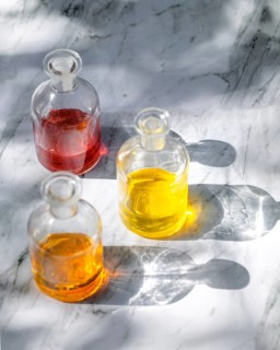 Overhead view of natural body oils infused with plants like calendula and rose. The image captures