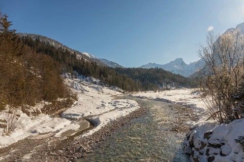 The Riss creek flowing through a snow covered landscape in the Eng valley. Sunny day with blue sky