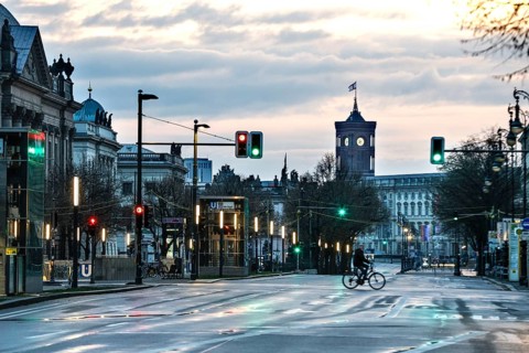 A cyclist rides along the empty boulevard Unter den Linden in the early morning, with a view of the