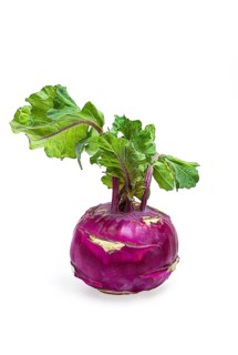 Fresh purple kohlrabi with vibrant green leaves displayed on a white background in a studio setting