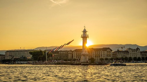 Captivating view of a golden sunset silhouetting the lighthouse on Lake Geneva, with clear skies
