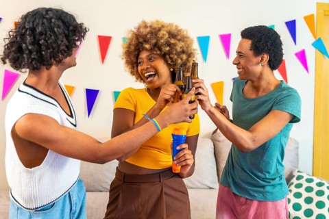 Multi-ethnic friends having fun toasting with beer and singing in a karaoke party at home