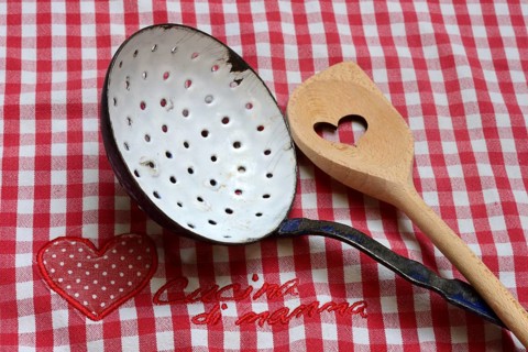 Dish drainer and cooking spoon on kitchen towel with lettering 'Cucina di mamma'
