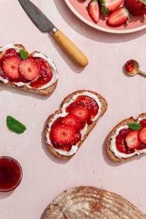 Top view of toasted bread with cream cheese and fresh strawberries, perfect for a summer brunch.