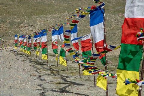 Colorful prayer flags flutter in the mountain breeze of Spiti Valley, India, adding vibrant hues to