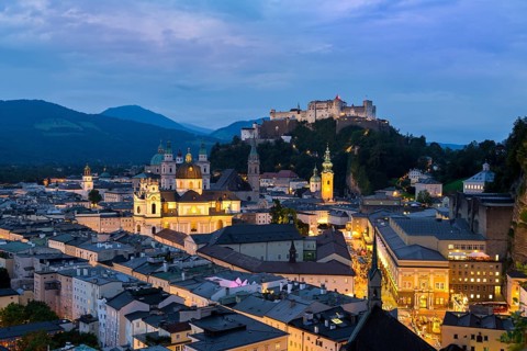 Evening lights of Salzburg with the majestic Hohensalzburg Fortress and the Alps in the soft