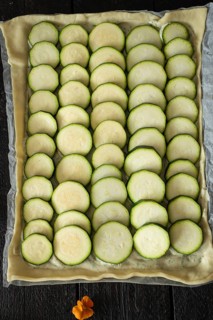 A visually appealing tart with neatly arranged zucchini slices on a pastry base, accompanied by a