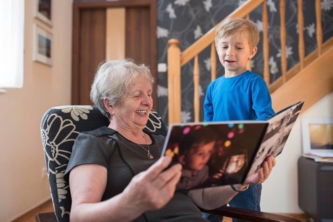 Grandmother and grandson watching photo album with the grandson pictures on the cover