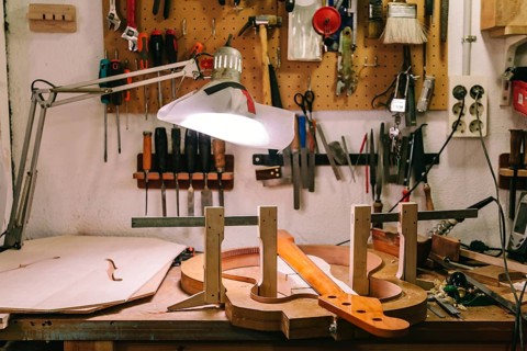 A detailed view of a luthier's workshop where a bass guitar is being meticulously crafted. Tools