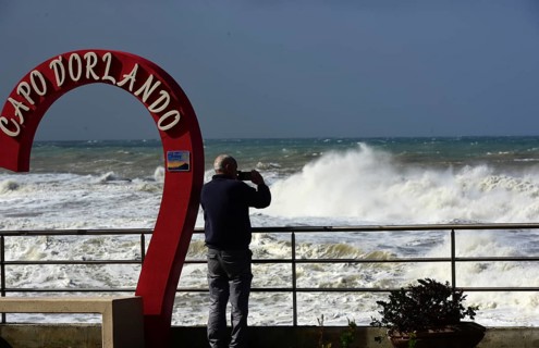 Severe weather waves on the quay wall of Capo D'Orlando. A person photographs the stormy sea on the