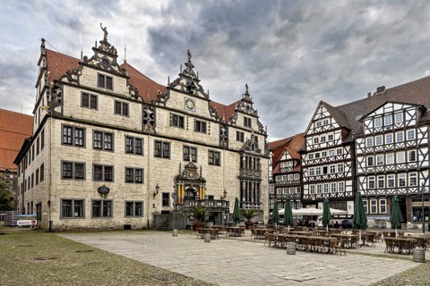 Historic market square with half-timbered houses and ornate buildings under a cloudy sky, The