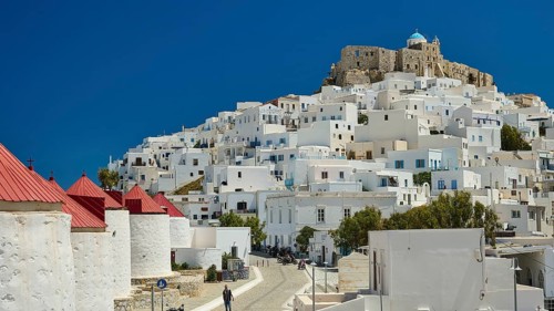 View of a compact settlement with white buildings under a clear, bright blue sky, windmills,