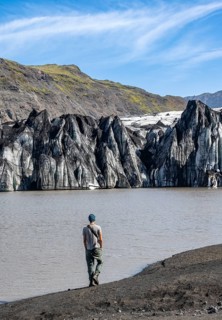 Tourist at the lakeside of a glacier lagoon, glacier tongue with crevasses and lake,