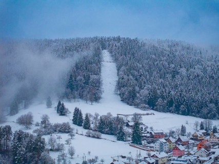 Wooded hills in winter with visible ski slope and dense fog, Enzklösterle, district of Calw, Black