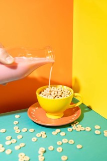 A dynamic and vivid image featuring milk being poured into a bright yellow cup filled with cereal,