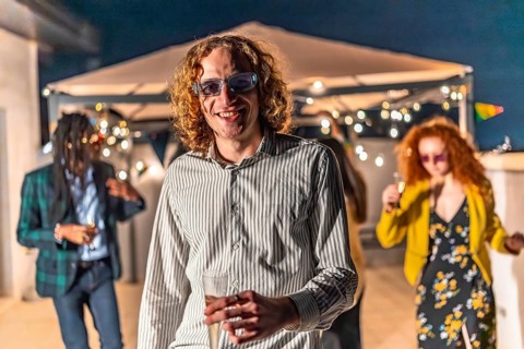 Young man with sunglasses and a glass of champagne at night party with friends