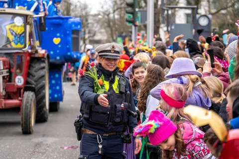 Rose Monday parade in Düsseldorf, policemen on duty at the street carnival, with flower