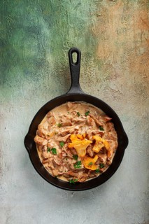 Fried chanterelle mushrooms, in cream sauce, in a cast-iron pan, homemade, no people