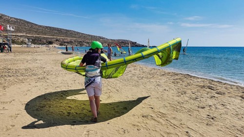 Person carrying sail on the beach in sunny weather, sea in the background, surfers paradise,