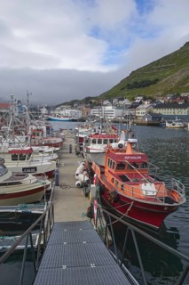 A busy harbour with fishing boats, flanked by a hill and a town, Honningsvag, Norway