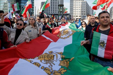 Iranians demonstrate with a large imperial Iranian flag on the day of the US and Israeli attack on