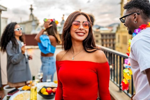 Chic beauty woman smiling while friends partying outdoors in a rooftop in the background