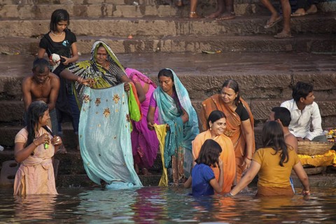 Old Indian women bathing in polluted water of the Ganges river at Varanasi, Uttar Pradesh, India