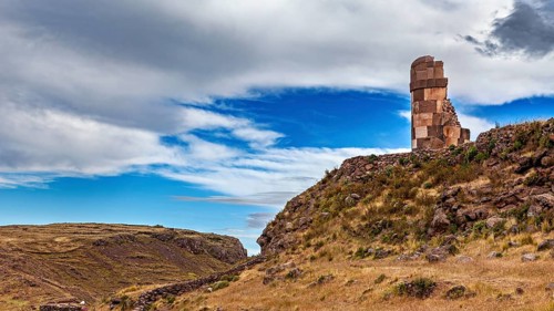 Historic stone ruin on a hill against a blue, cloudy sky, The Chullpas of Sillustani near Puno in