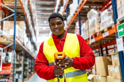 Frontal view of a latin man with modern scan machine in a storage warehouse
