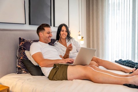 Tranquil scene of a couple lying on the bed using laptop together