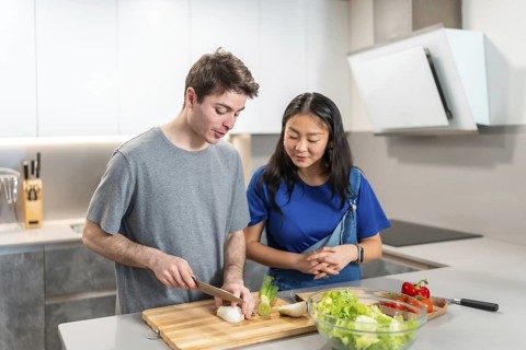 Multiethnic couple enjoying quality time together while preparing a healthy salad in their modern
