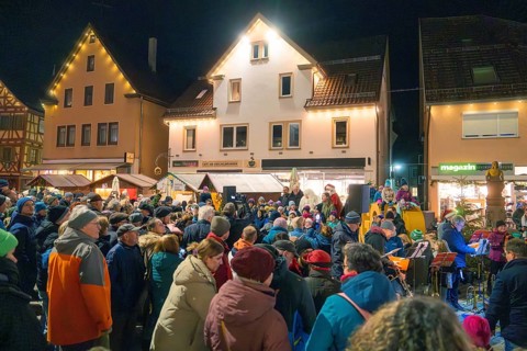 A joyful crowd gathers at night at a market decorated for Christmas, Christmas market, Nagold,