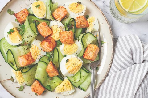 Delicious salmon and egg salad served on a plate with fresh cucumber and herbs for a healthy meal