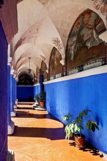 A corridor with blue walls and decorative frescoes under an elegant vaulted ceiling, The Santa