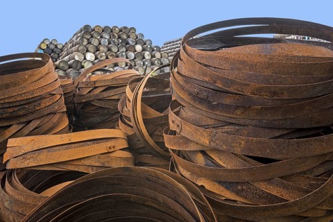 Pile of rusty metal hoops in front of stacks of discarded whisky casks, barrels, Speyside
