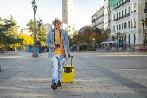 A Latino transgender man walks confidently through a city street, capturing moments with his