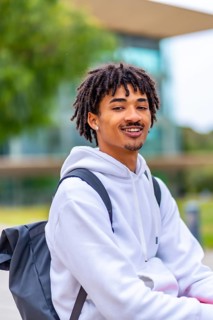 Vertical portrait of a cool african american male young student with dreadlocks smiling at camera
