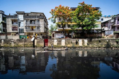 Ragpickers searching recyclable materials using a boat at a dirty polluted canal, in Guwahati,