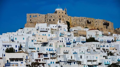 An old castle overlooks a town of white houses under a clear sky, Querini Castle, Chora, Astypalea,