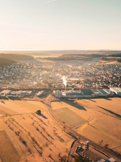 Town with neighbouring fields and industry in a hilly landscape seen from the air, Althengstett,