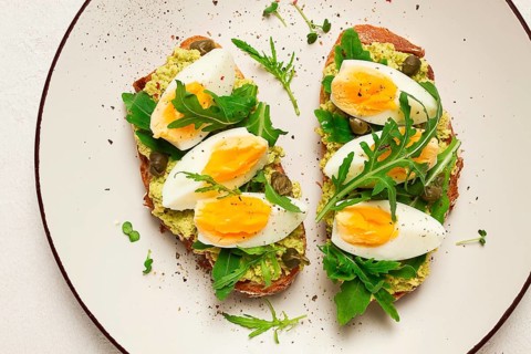 Sandwich with mashed avocado, boiled egg, and arugula, on bread, homemade, breakfast