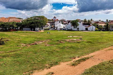 Wide meadow with a view of a small town and a church under a cloudy sky, the historic downtown of