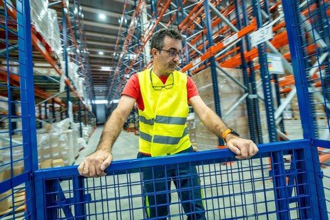 Three quarter length photo of a mature man in protective gear working in a storage warehouse