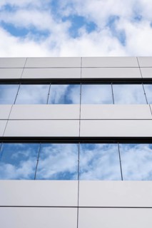 A close-up view of a modern building's glass and metal facade, featuring reflective windows against