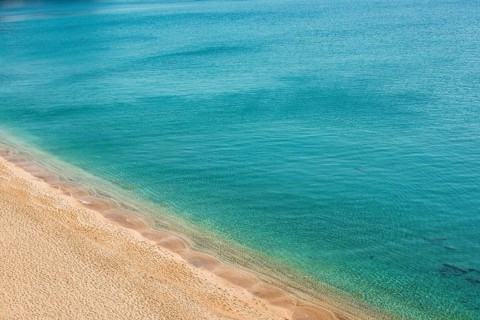 A tranquil view of Paleochori Beach on Milos Island, Greece, showcasing golden sand meeting