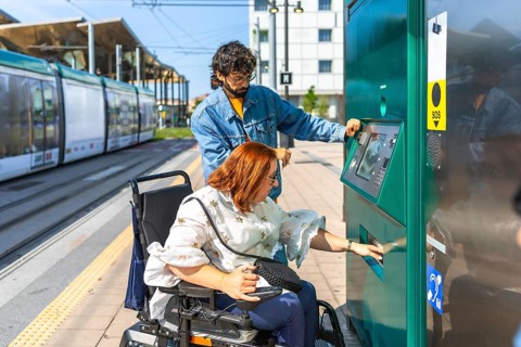 Young redhead woman with her male friend buying a ticket at automatic ticket machine at a tram